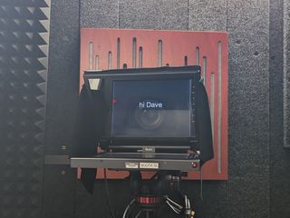 Teleprompter in front of camera lens with 'hi Dave' displayed.